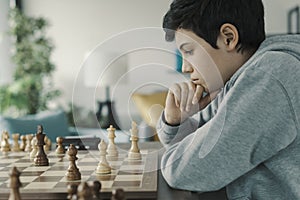 Focused boy playing chess at home