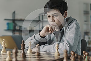 Focused boy playing chess at home