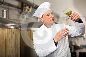 Focused brewer checking quality of hop pellets in brewery