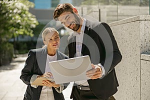 Focused business colleagues working outdoor on laptop with new startup project