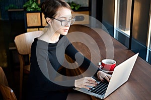 Focused business woman sit on cafe working on laptop, concentrated serious female working with computer and notebook in coffee sho