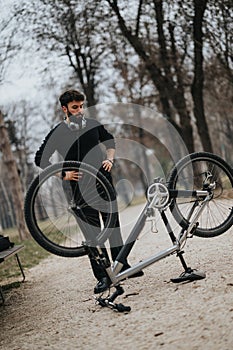 Focused businessman in casual attire repairing a bicycle in a park