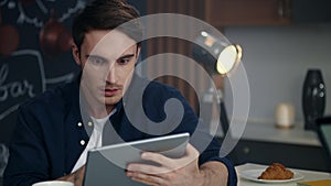 Focused businessman getting good news on tablet computer at remote workplace.