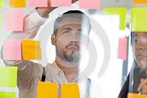 Focused businessman looking at sticky papers, brainstorming in office