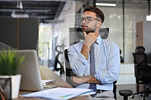 Focused businessman thinking at modern office into report file calculating stock market earnings, startup business