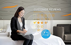 Focused businesswoman perusing through customer reviews on her laptop while sitting comfortably on a bed in a calm and serene