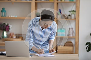 Focused busy millennial entrepreneur woman signing paper document