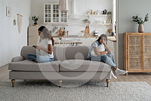 Focused busy woman mother using smartphone during family time child daughter at home