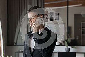 Focused busy young executive man talking on cellphone in office