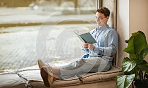 Focused calm smart european young man student in glasses read book, enjoy peace