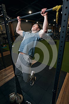 Focused calm young male gymnast doing pull-ups