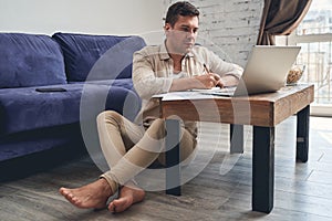 Serious man sitting barefoot on the floor photo