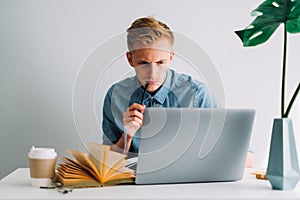 Focused caucasian man college student studying with books and laptop distantly photo