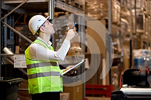 focused caucasian man worker doing stocktaking of products on shelves in warehouse