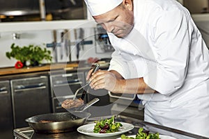 Focused chef prepares steak dish at gourmet restaurant