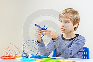Focused child with 3d printing pen creating a plane