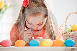 Focused child creating drawings on colorful dyed eggs