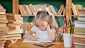 A focused child is engaged in the library. Blond white girl with ponytails 8-10 years old in the library.