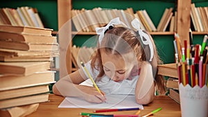 A focused child is engaged in the library. Blond white girl with ponytails 8-10 years old in the library.