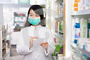 Focused Chinese female with notebook in pharmacy