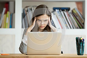 Focused concerned girl student learning difficult exam with lapt