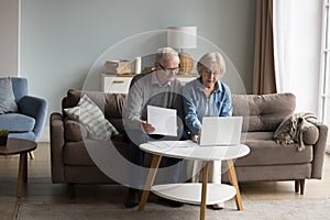 Focused couple of older senior pensioners checking domestic financial papers