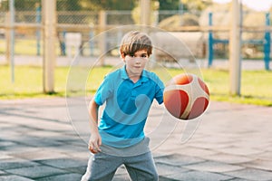 Focused cute boy athlete leads the ball in a game of basketball. A boy plays basketball after school. Sports, healthy