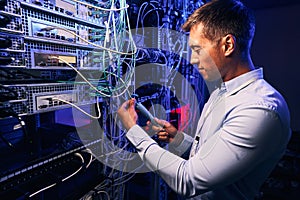 Focused data center employee checking cabling infrastructure