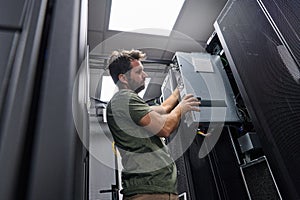 Data center technician installing server hardware and cabling in a server rack during maintenance work