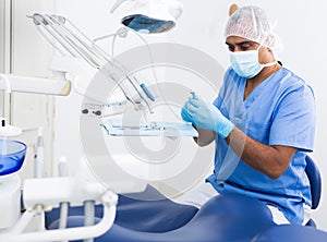 Focused dentist checking and arranging tools in dental office