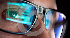 Developer coder looking on computer, programming code reflecting in glasses.
