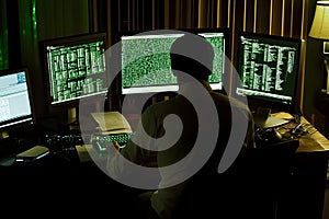 Focused developer coding with multiple monitors in a darkened room