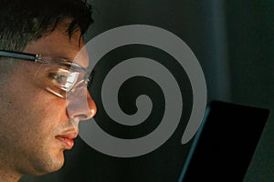 Focused developer wearing glasses works intently on a laptop screen. Concept of coding, cybersecurity, and technology skills in