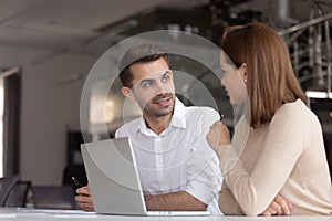 Focused diverse employees talk working at laptop together