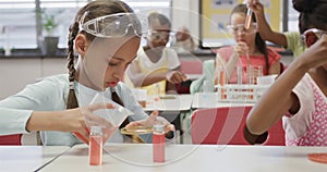 Focused diverse schoolgirls doing experiments in elementary school chemistry class, slow motion