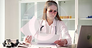 Focused doctor examines medical history looking in laptop