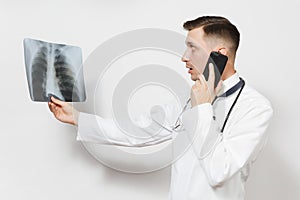 Focused doctor man with X-ray of lungs, fluorography, roentgen, talking on mobile phone isolated on white background