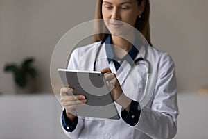 Focused doctor, physician using tablet computer, giving online virtual consultation