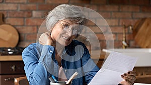 Focused elderly latin woman engaged in reading letter from bank