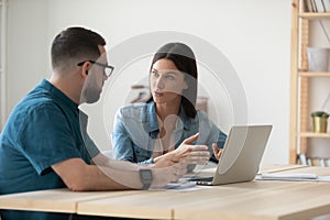 Focused employees brainstorm using laptop at office meeting