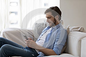 Focused engaged millennial young guy with mobile phone