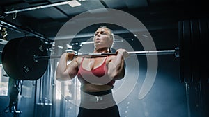 A Focused Female Bodybuilder Lifts Barbell with Heavy Weights in a Hardcore Gym Workout. Portrait of