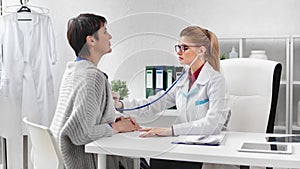 Focused female cardiologist listening heartbeat of mature woman patient using stethoscope