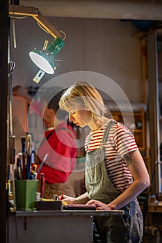 Focused female carpenter draws up an estimate to produce handmade furniture stands in carpentry shop