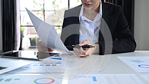 Focused female economist working with statistics document at office desk