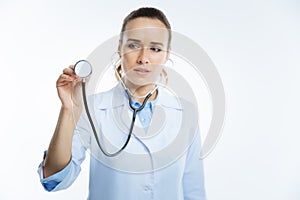 Focused female looking doctor listening to heart with stethoscope