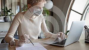 Focused female manager in protective mask gloves working on computer.