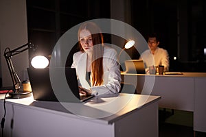 Focused female office worker checking business reports trying to finish deadline