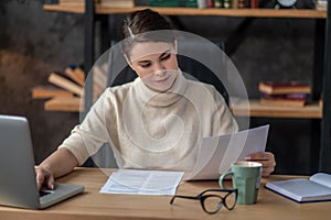 Focused female reading a contract at the writing table