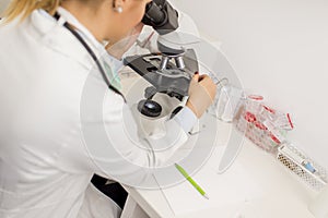 Focused female science student looking in a microscope in a laboratory